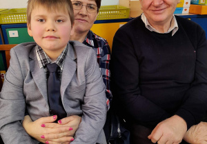 Hubert M. siedzi na kolanach u babci, zadowolony dziadek siedzi obok nich.