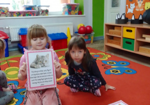 Julia prezentuje ilustracje kota i tekst z ciekawą informacją o tych zwierzętach domowych, obok Natalia.