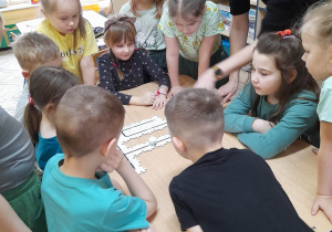 Dzieci wraz z nauczycielem oglądają puzzle z Edu Sense, po których porusza się ozobot.