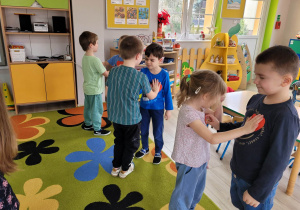 Dzieci z grupy Biedronek stoją w parach. Przedszkolaki mają zamknięte oczy oraz trzymają prawą dłoń w miejscu serca kolegi/koleżanki. Dzieci słuchają bicia serca.