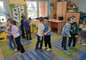 Ciąg dalszy zabawy ruchowej na dywanie z piosenką. Dzieci w parach wykonują wskazane ćwiczenie - przykładają wywołane części ciała, tutaj ucho do ucha.