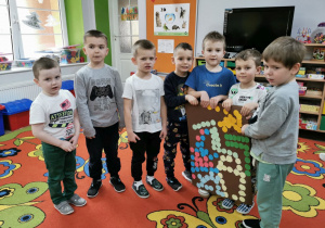 Mateusz, Gabryś, Kacper, Antoś, Franek, Eryk i Kacper P stoją na dywanie trzymają w rękach swoją zakodowaną pracę.