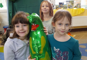 Amelia, Winicjusz i Amelia pozują do zdjęcia z balonem w kształcie dinozaura.
