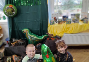 Bruno i Oliwia pozują do zdjęcia z foliowym balonem w kształcie dinozaura.