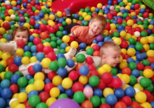 Grupka dzieci podczas zabawy w basenie z kolorowymi kulkami.