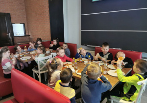 Zdjęcie grupowe na którym widać zadowolone "Słoneczka" w trakcie zjadania pizzy.