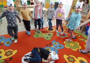 Witek w środku koła podczas zabawy „Stary niedźwiedź”, wokół dzieci w kole wiązanym w opaskach z białym misiem na głowach.