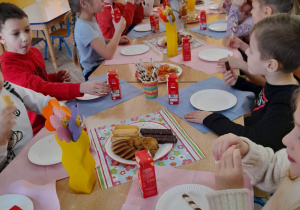 Dzieci siedzą przy wspólnym stole podczas słodkiego poczęstunku.