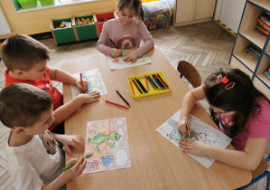 Dzieci kolorują obrazki z maskotką programu - Dinkiem.