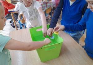 Dzieci wkładają do pojemnika z wodą gwiazdki z rogami złożonymi do środka.