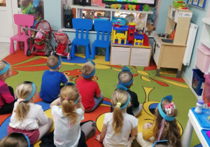 Dzieci siedzą na dywanie i oglądają film edukacyjny pt. "Zdrojek i pory roku".