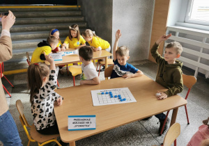 "Słoneczka" siedzą przy stoliku i komunikują ukończenie pierwszego zadania.