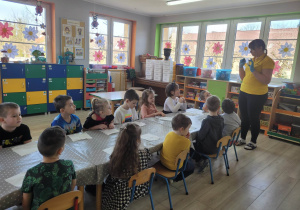 Dzieci z grupy Biedronek siedzą przy stole. Pracownica cukierni tłumaczy przedszkolakom na czym będą polegały dzisiejsze warsztaty.