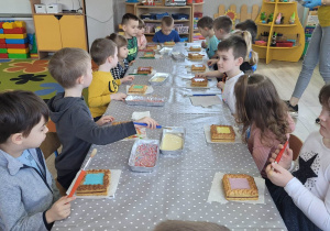 "Biedronki" siedzą przy jednym długim stole. Każde dziecko ma przed sobą ciasto - świątecznego mazurka.