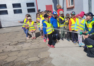 Dzieci z grupy "Biedronek" w trakcie pokazów używania węża strażackiego.