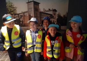 Dzieci podczas zwiedzania Pałacu Saskiego stoją na tle zdjęcia dawnego Dworca Kolejowego.