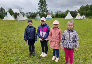 Igor, Ala, Oliwia i Ala stoją obok siebie na trawie. W tle namioty indiańskie, drzewa.