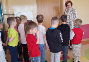 Dzieci wraz z Panią nauczycielką stoją przed drzwiami sali lekcyjnej.