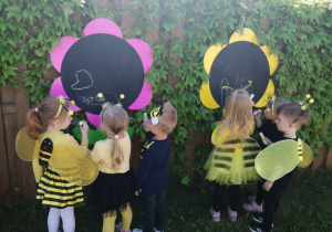 Grupka dzieci rysuje kredą na tablicy Pszczółkę Maję.