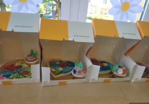 Na fotografii widać pudełka pełne słodkich wypieków ozdobionych przez dzieci.