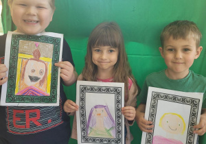 Aruś, Zosia i Eryczek prezentują namalowane przez siebie portrety swoich mam.