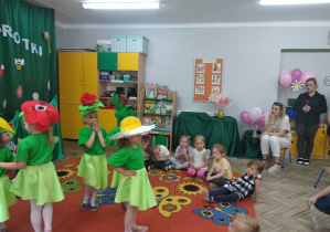 Dziewczynki – kwiatki prezentują swój taniec, grupa maluchów z P. Moniką i P. Małgosią, podziwiają występ.