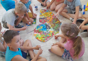 Dzieci z grupy "Słoneczka" siedzą na dywanie i prezentują ozdobione skrzydło motyla.
