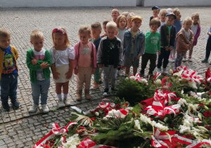 Dzieci stoją w rozsypce przed pomnikiem Bohaterów Bitwy nad Bzurą.