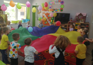 Zabawa w kole z chustą animacyjną i kolorowymi balonami w kropki.