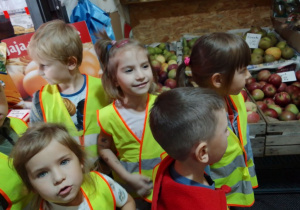 "Biedronki" oglądają owoce i warzywa wystawione na straganie.