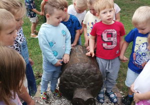 Grupka dzieci stoi przy rzeźbie żołędzia.