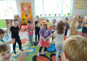 Lena w kapeluszu Pani Jesieni tańczy z Wiktorią. Wokół "Biedronki" klaszczą w ręce, w tle jesienna dekoracja.