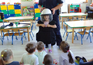 Amelia w kamizelce ochronnej i kasku, obok Pan policjant.