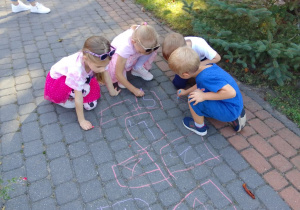 "Biedronki" podczas wspólnego rysowania kolorową kredą na chodniku.