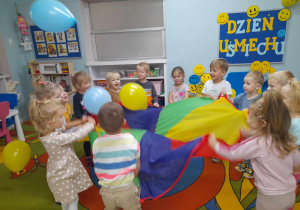 Dzieci z radością podrzucają balony na chuście animacyjnej.