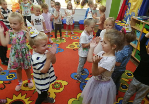 Dzieci stoją w rozsypce podczas zabawy przy muzyce.