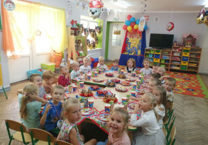 Dzieci siedzą przy wspólnym stole podczas słodkiego poczęstunku.