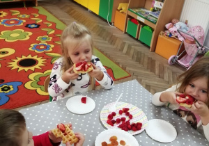 Grupka dzieci degustuje gofry z owocami.