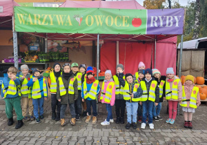 Wspólne zdjęcie dzieci z grupy "Słoneczek" przed sklepem owocowo-warzywnym.