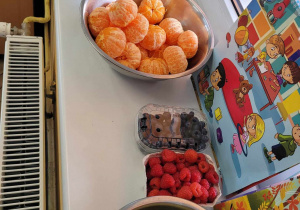 Na zdjęciu widać część z owocowych prezentów od właścicieli sklepu: jabłka, maliny, borówki i mandarynki.