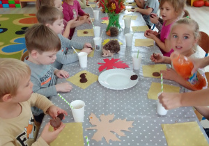 Dzieci przy długim stole podczas słodkiego poczęstunku.