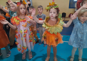 Dzieci z podniesionymi do góry rękoma tańczą przy muzyce.