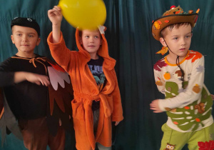 Gabryś, Filip i Julek ubrani w jesienne stroje tańczą obok siebie na balu.
