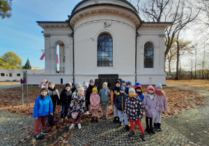 Przedszkolaki pozują do zdjęcia. W tle Muzeum Bitwy nad Bzurą, armata, drzewa.