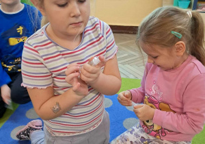 Anastazja i Gabrysia eksperymentują z wykorzystaniem strzykawek. Dziewczynki nabrały powietrze do strzykawek, przykryły palcem otwór z drugiej strony i próbują wcisnąć tłoczek do środka.