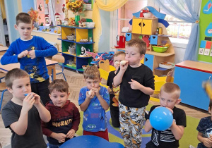 Grupka chłopców podczas zabawy badawczej z powietrzem nadmuchuje balony.