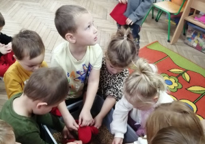 Dzieci na dywanie napełniają woreczki pestkami wiśni.