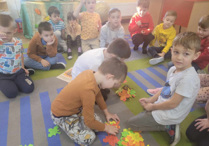 Dzieci z grupy "Słoneczek" z kolorowych liści układają legowisko dla jeża.