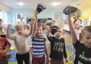 Przedszkolaki pokazują wizerunki odcisków niedźwiedzia w zabawie "Misiowa Łapa".