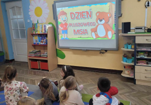 Dzieci oglądają film edukacyjny na tablicy multimedialnej.